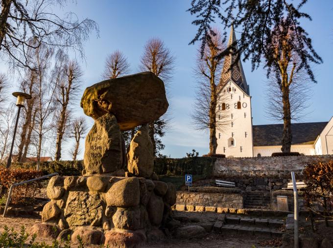 Mindesmærke for Genforeningen, udformet som en stendysse. Den blev afsløret i 1930. I baggrunden ses Broager Kirke. Mindesmærke for Genforeningen, udformet som en stendysse. Den blev afsløret i 1930. I baggrunden ses Broager Kirke.