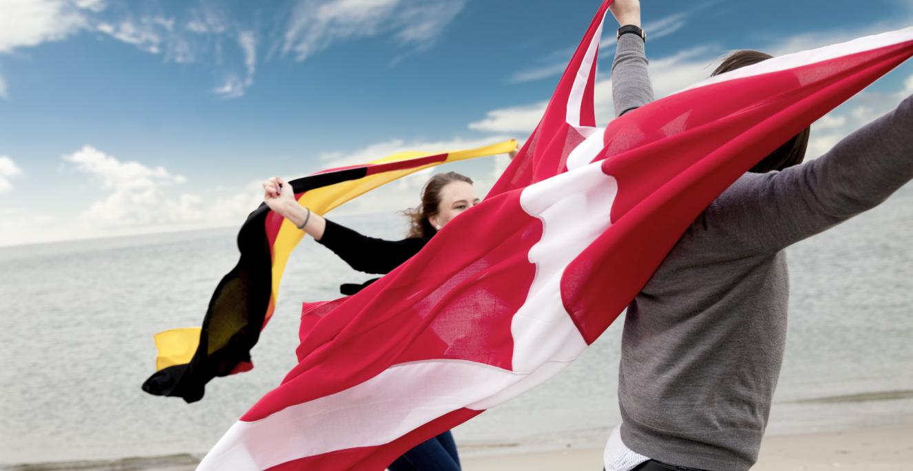 Unge på strand med dansk og tysk flag Unge på strand med dansk og tysk flag
